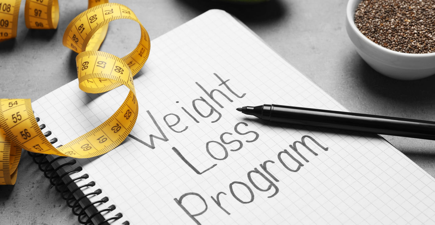 Weight loss program notebook with measuring tape, chia seeds and avocado